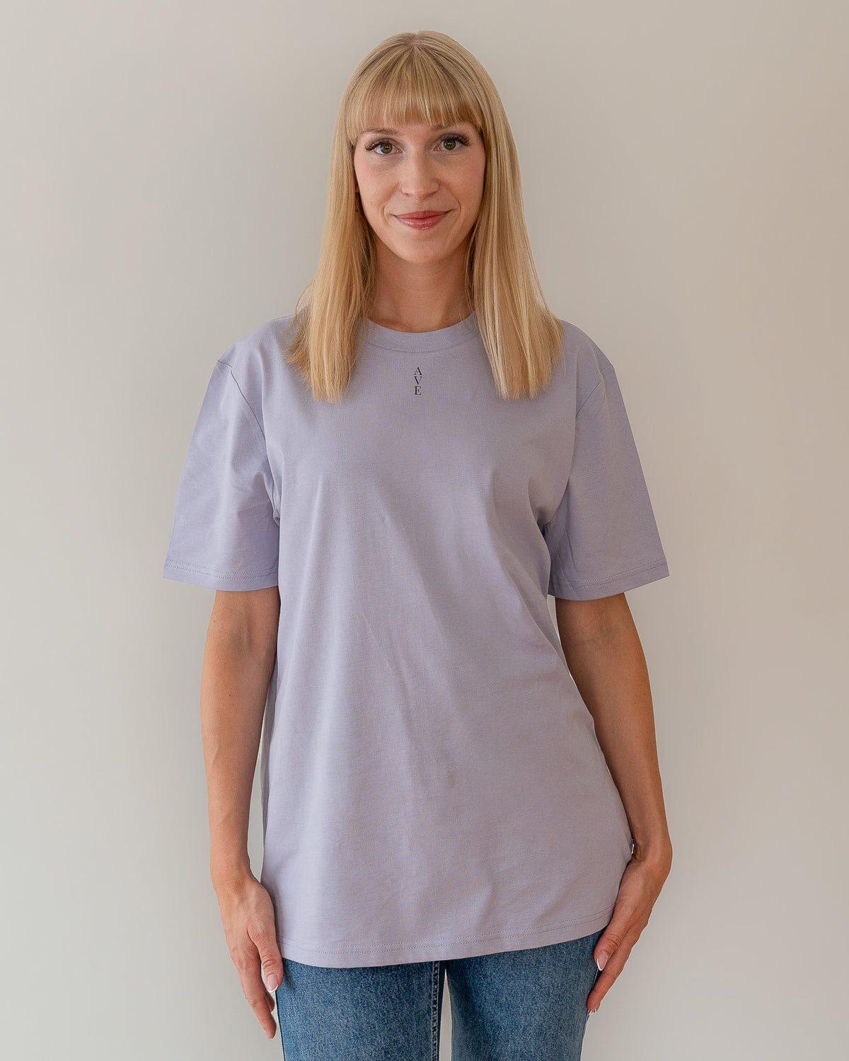 TESSERA t-shirt in lavender, worn by a woman, tucked loose, AVE lettering at the neckline