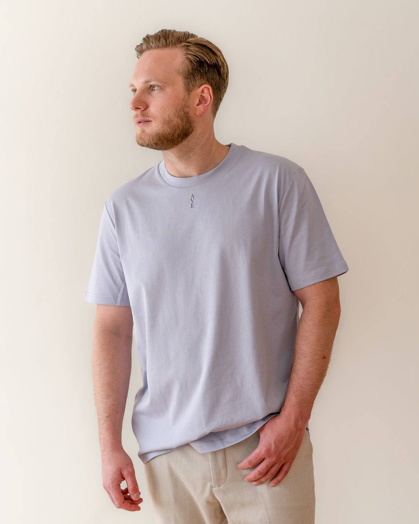 TESSERA t-shirt in lavender, worn by a man, worn loose, AVE lettering at the neckline