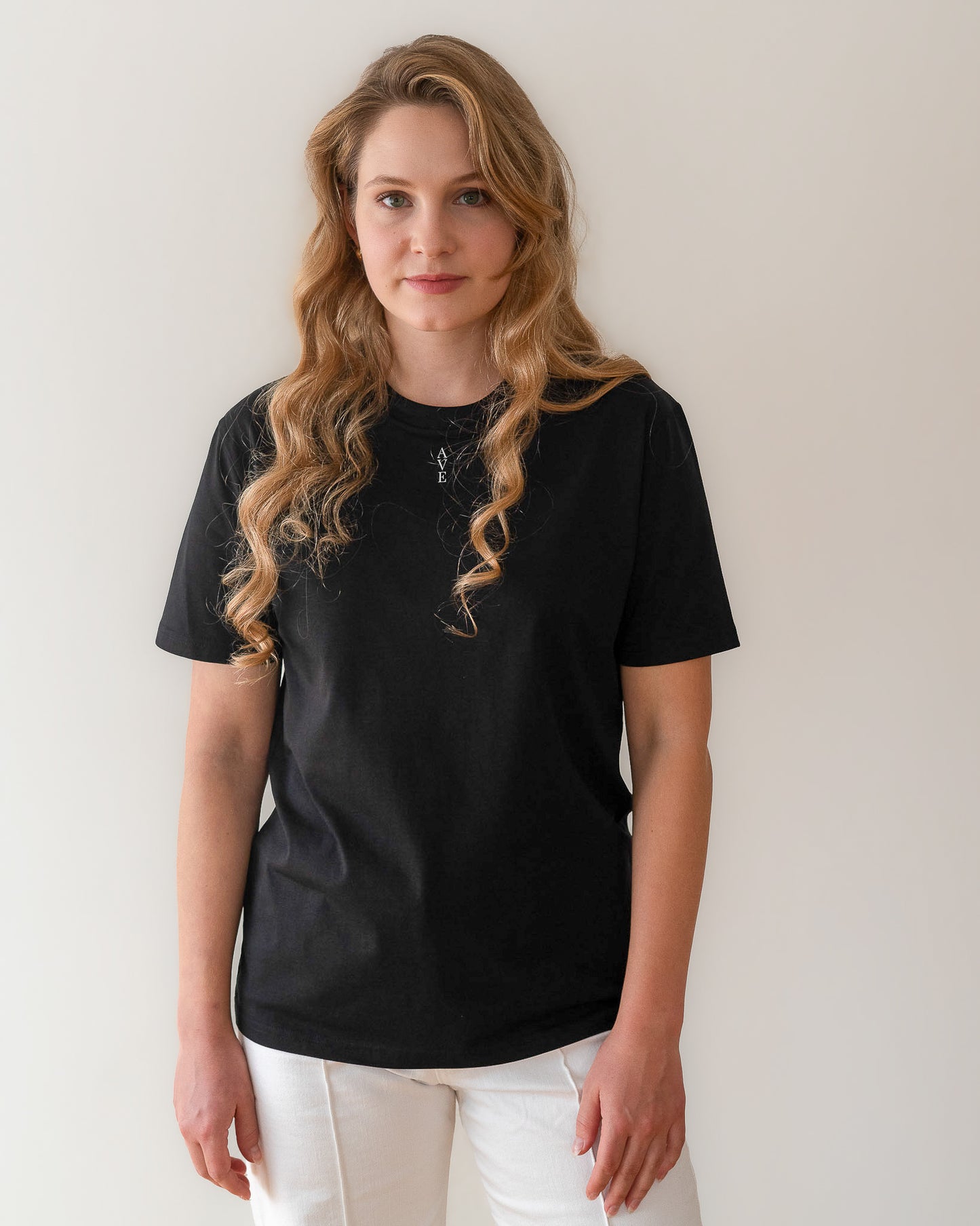 TESSERA t-shirt in black, worn by a woman, worn loose, AVE lettering at the neckline