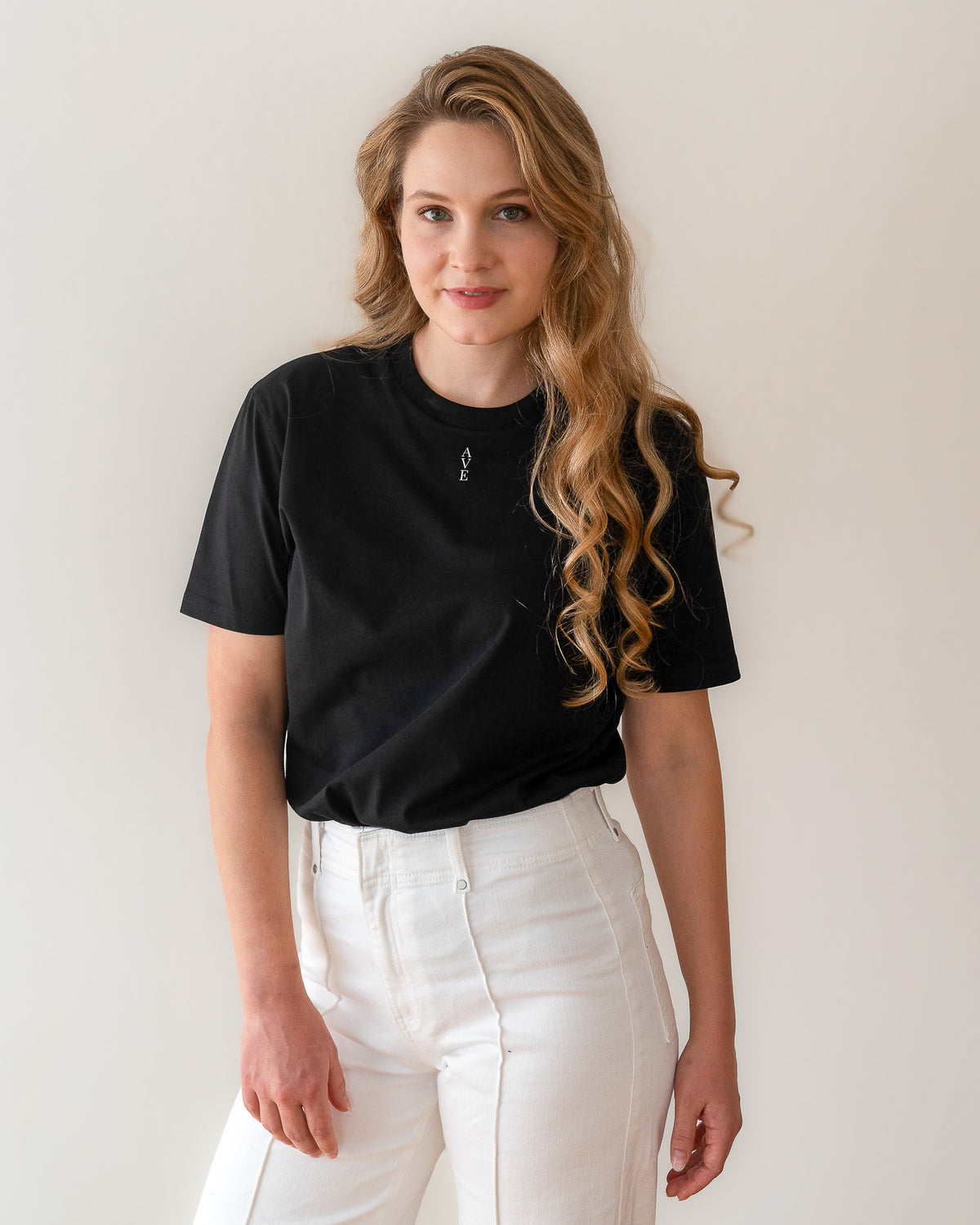 TESSERA t-shirt in black, worn by a woman, tucked in, AVE lettering at the neckline