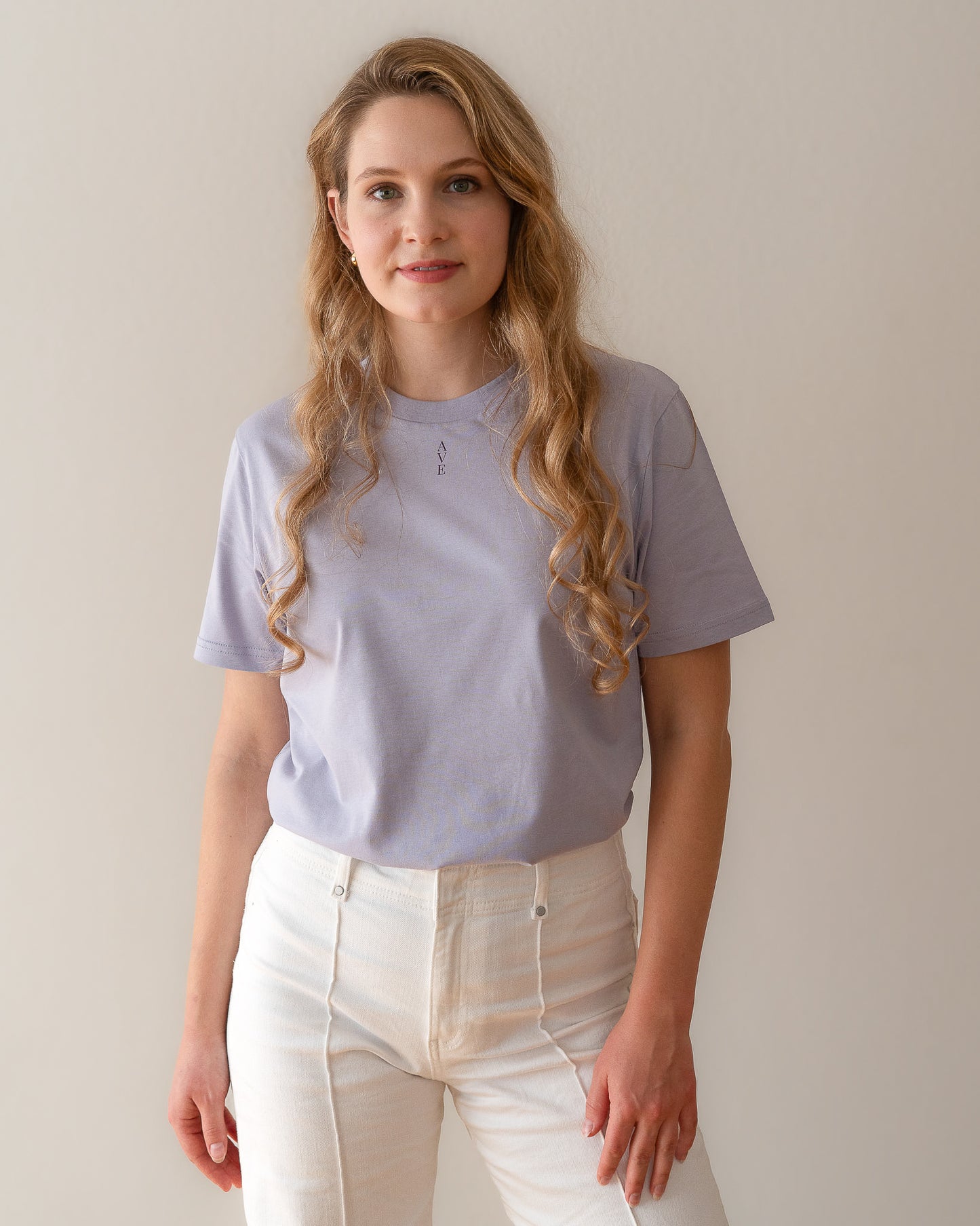 TESSERA t-shirt in lavender, worn by a woman, tucked in, AVE lettering at the neckline