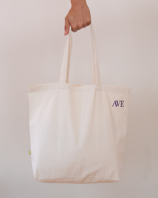 AVE tote bag in beige, held by hand, AVE embroidery in the corner